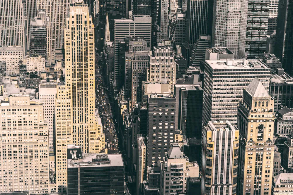 An aerial view of densely packed Midtown Manhattan towers, looking straight down a narrow avenue.